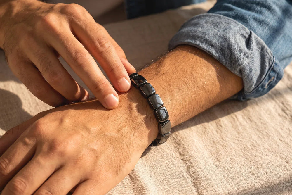 Close-up of a man's wrist wearing the black hematite bracelet in warm evening light